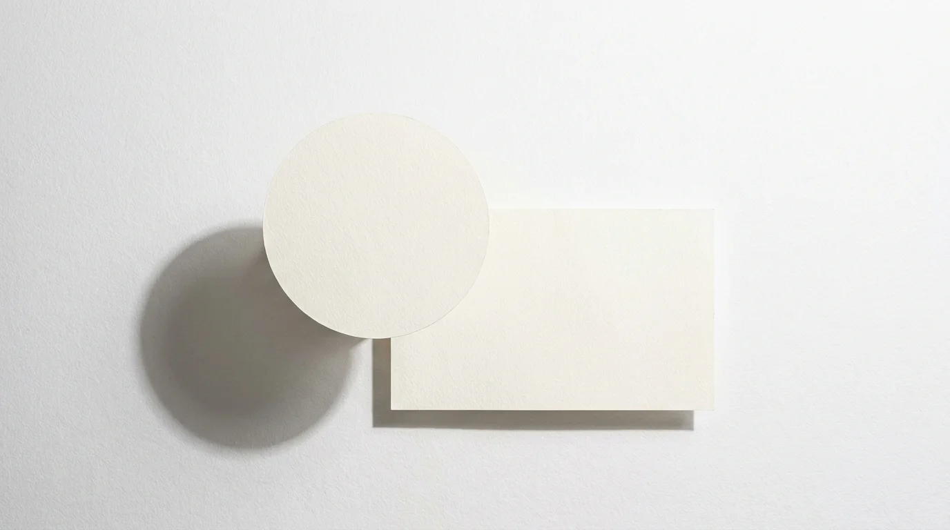 An abstract paper-craft composition showing a few shapes surrounded by vast white space.