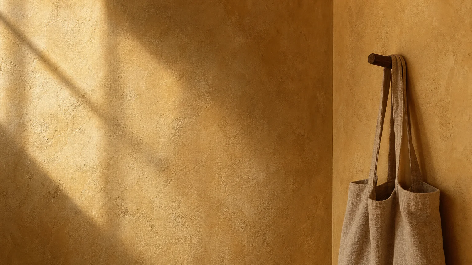 Close-up of a wall with textured, earth-toned Roman clay plaster, showing soft shadows and hand-applied details.