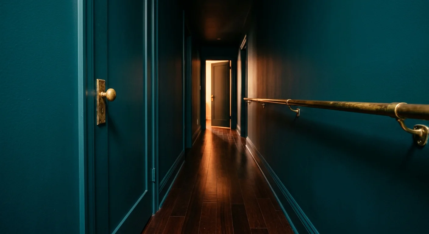 A perspective view of a midnight teal hallway with warm brass hardware and polished mahogany wood floors.