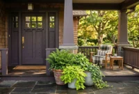 An inviting craftsman-style front porch featuring a charcoal-plum painted door, terracotta planters, and warm golden hour sunlight.