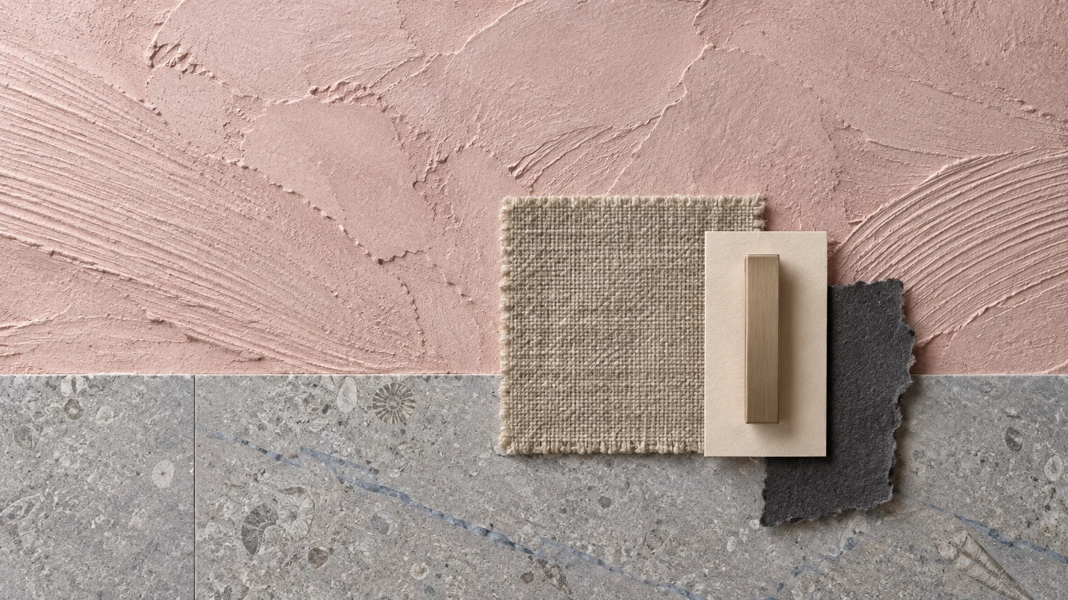 Textured pink plaster wall above gray fossil stone tile, overlaid with fabric, paper, and metal hardware swatches.