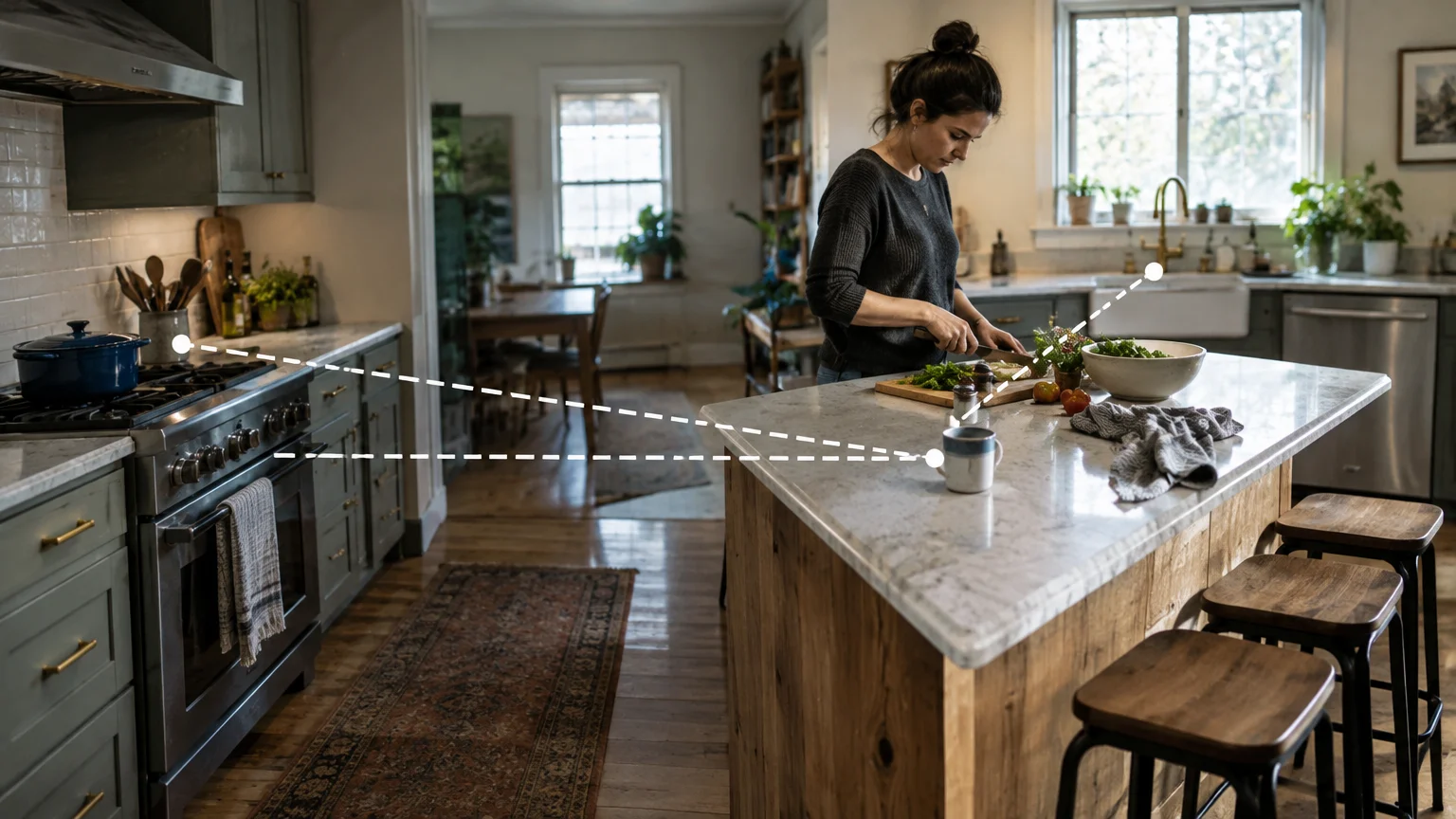 Woman chopping vegetables at a kitchen island with white dotted lines connecting the island, stove, and sink.