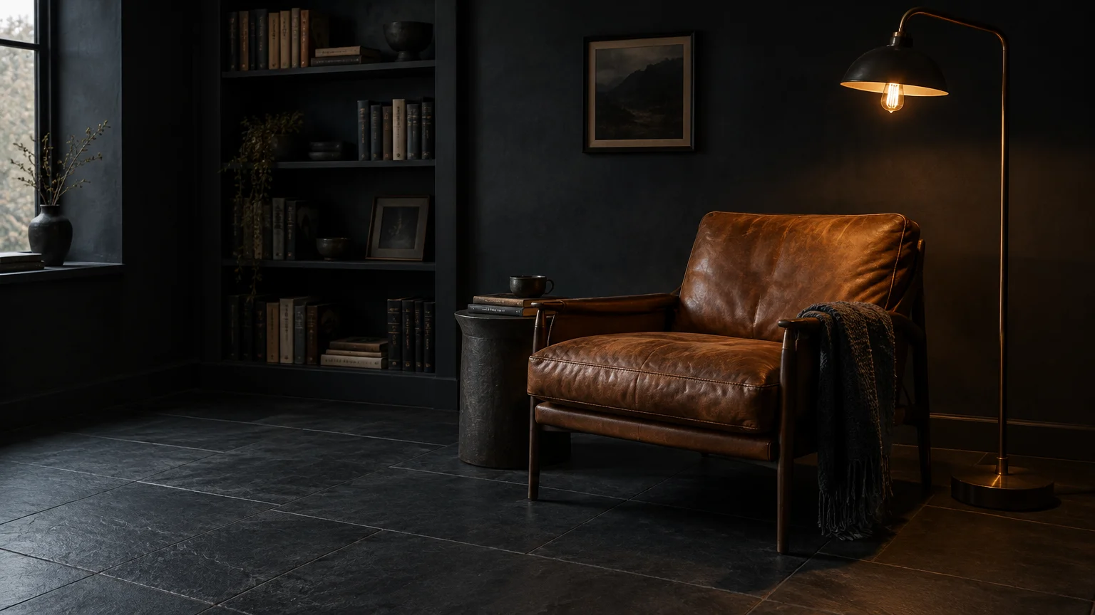 Dark room with slate gray tile floors, charcoal walls, a brown leather armchair, a side table, and a floor lamp.