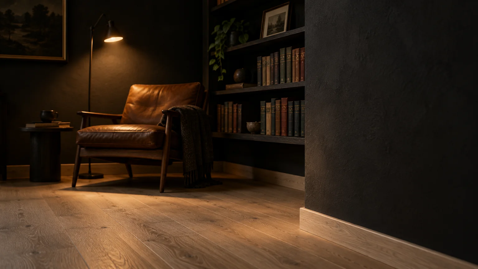 Dark charcoal room featuring light wood floors, a leather armchair under a floor lamp, and built-in bookshelves.